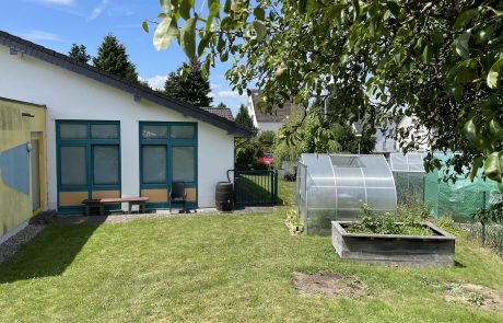 Bild sonniger Außenbereich Kita Höchstenbach mit Gemüsebeet und Gewächshaus
